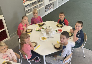 dzieci siedzą przy zastawionym stole